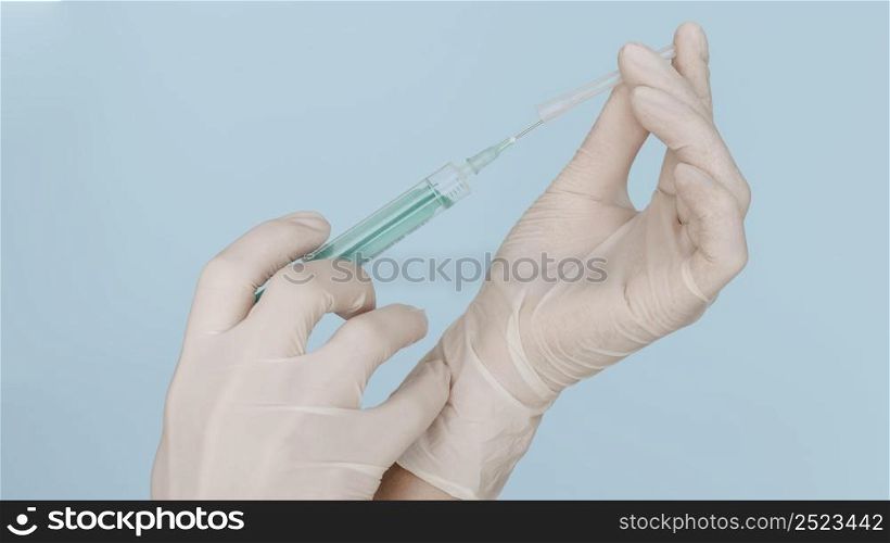 hands with gloves holding syringe