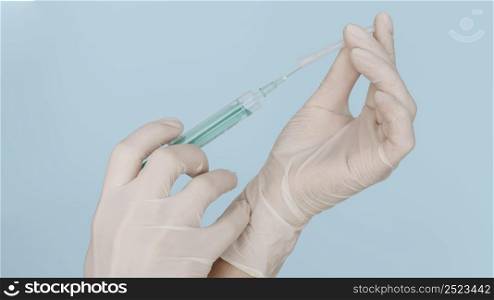 hands with gloves holding syringe