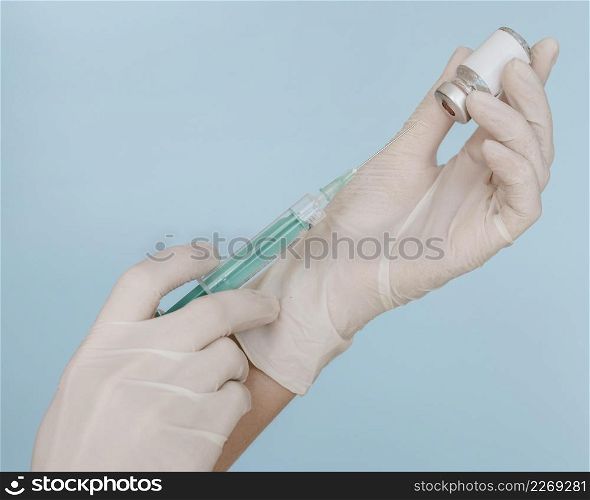 hands with gloves holding syringe with vaccine bottle
