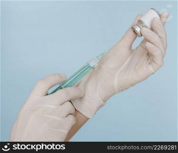 hands with gloves holding syringe with vaccine bottle