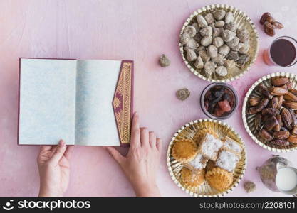 hands with koran table with sweets