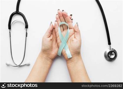 hands with light blue ribbon near stethoscope