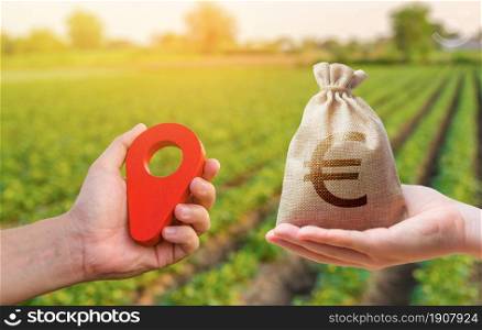 Hands with location pin and euro money bag. Land market. Buying and selling land. Estimation cost of plots. Legal regulation of property. Agriculture agribusiness. Transport and construction industry.