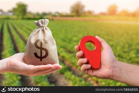 Hands with location pin and money bag. Buying and selling land. Land market. Estimation cost of plots. Legal regulation of property. Agriculture agribusiness. Transport and construction industry.