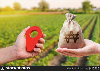 Hands with location pin and south korean won money bag. Land market. Agriculture agribusiness. Transport and construction industry. Buying and selling land. Estimation cost of plots.