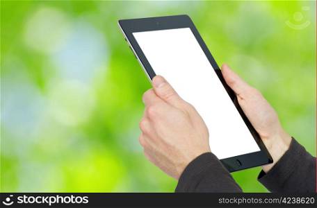 hands with tablet computer on green