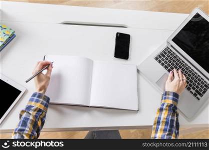 hands woman writing notebook touching keyboard laptop