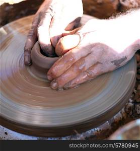 Hands working with clay on pottery wheel