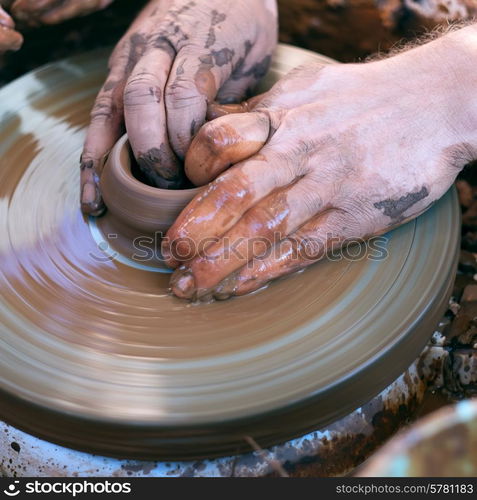 Hands working with clay on pottery wheel