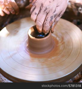 Hands working with clay on pottery wheel