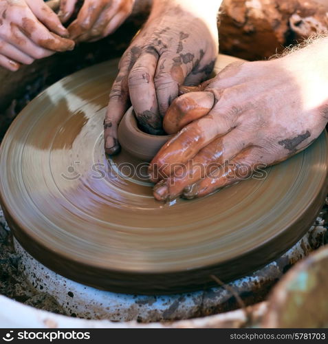 Hands working with clay on pottery wheel