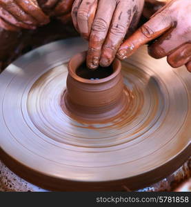 Hands working with clay on pottery wheel