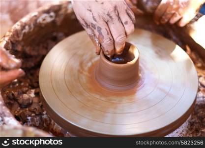 Hands working with clay on pottery wheel