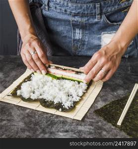 hands wrapping ingredients sushi mat