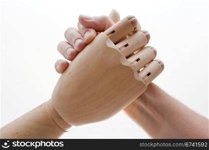 Handshake between a human hand and a wooden hand