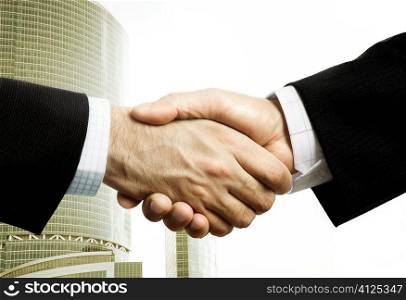 handshake of two businessman on modern building background, selective focus on nearest part