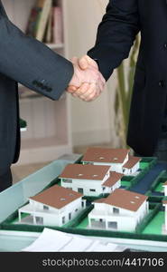 Handshake over a model housing estate