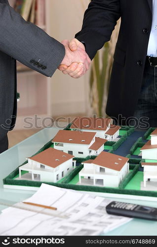 Handshake over a model housing estate