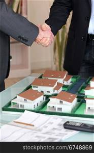 Handshake over a model housing estate