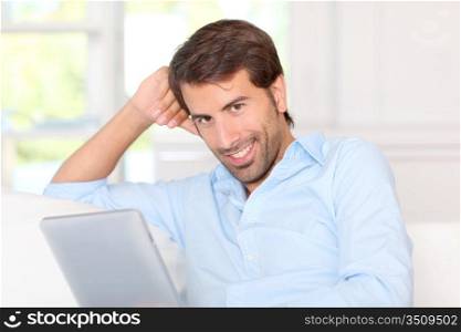 Handsom guy using electronic tablet at home
