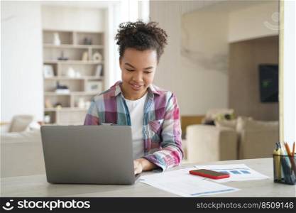 Handsome afro girl is studying remote on quarantine. Happy teenage pupil is sitting in front of laptop having online conference. Remote study at school or college. Internet lesson session.. Handsome afro girl is studying remote on quarantine. Happy teenage girl has internet lesson session.
