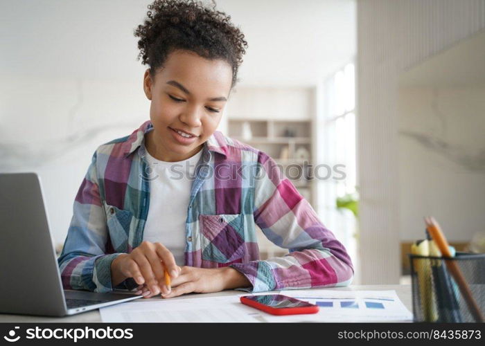 Handsome afro schoolgirl is studying remote at home and doing homework. Teenage girl is sitting at the desk in front of computer having online exam. Remote study at school or college via zoom.. Handsome afro schoolgirl is studying remote at home and doing homework. Online exam.