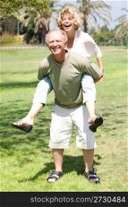 Handsome aged man gives his lovable wife piggy-ride