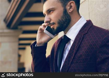 Handsome and fashionable man with a beard talking on the phone in close-up