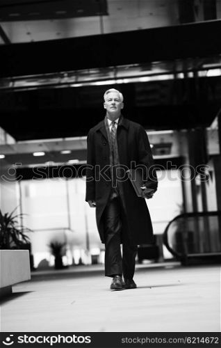 handsome and sucessful senior business man walking in modern office interior