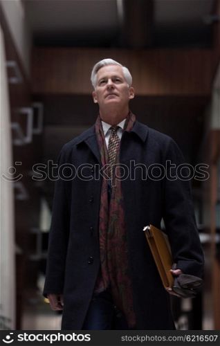 handsome and sucessful senior business man walking in modern office interior