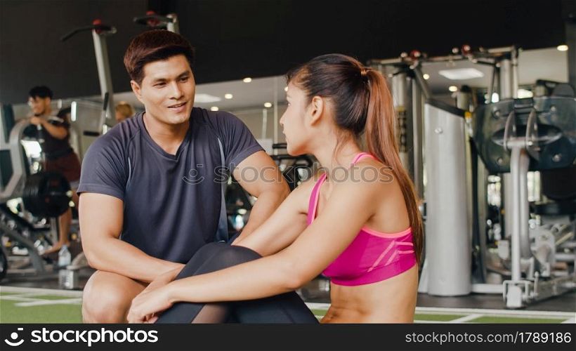Handsome asian guy personal trainer focus body weight training to lady customer, People training in a gym, Personal trainer in a fitness class, Fitness in gym, sport and healthy lifestyle concept.