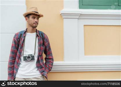 Handsome Asian man tourist Standing at wall While wearing a straw hat at Attractions in Bangkok, Thailand, Solo travel and backpacker concept