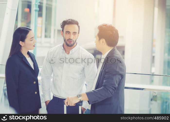 handsome asian young businessman and businesswoman three people in classic suits talking and smile with discussion standing outside the office building, teamwork with business concept.