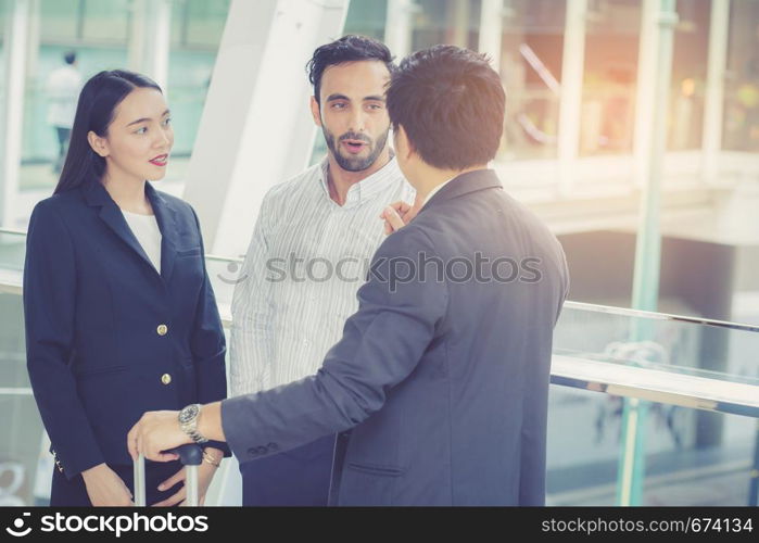 handsome asian young businessman and businesswoman three people in classic suits talking and smile with discussion standing outside the office building, teamwork with business concept.