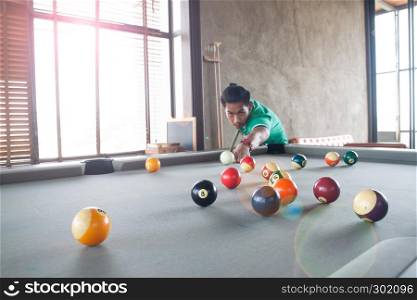 Handsome asian young man playing pool at home, Selective focus on ball