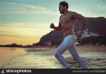 Handsome athlete running along the seaside
