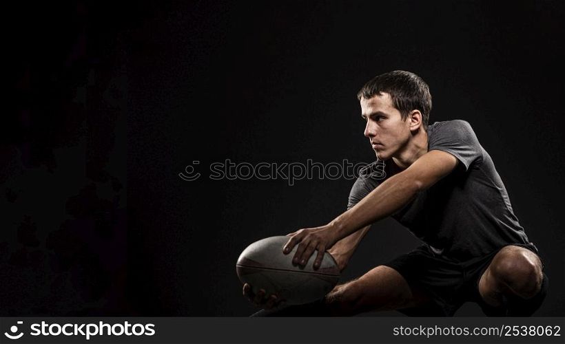 handsome athletic male rugby player holding ball with copy space