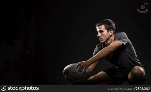 handsome athletic male rugby player holding ball with copy space