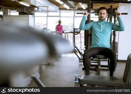 Handsome athletic man training pumping up back muscles pull up