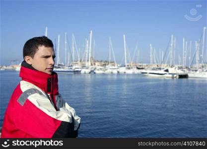 Handsome boy on blue marina harbor with red marine coat