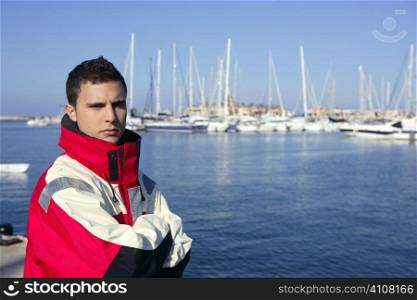 Handsome boy on blue marina harbor with red marine coat