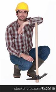 handsome bricklayer with arm resting on pickaxe