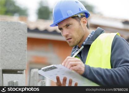 handsome builder writing on clipboard