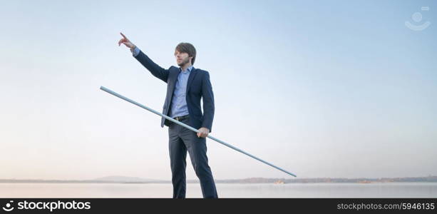 Handsome businessman holding long stick