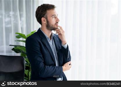Handsome businessman in black suit stand confidently in his modern office portrait, deep in thought about business with pensive gazing expression, thinking strategically about his next move. Entity. Businessman in black suit stand confidently in modern office portrait. Entity