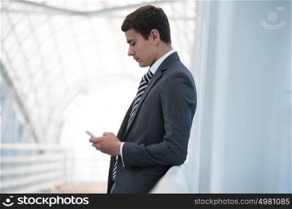 Handsome businessman in suit using smartphone in office