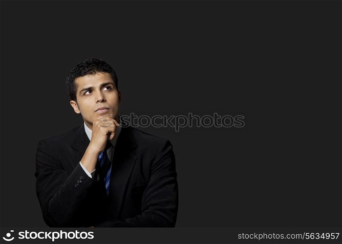 Handsome businessman looking away over black background