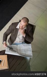 Handsome businessman or manager in office building reading newspaper view from above