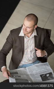 Handsome businessman or manager in office building reading newspaper view from above