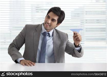 Handsome businessman playing with paper airplane
